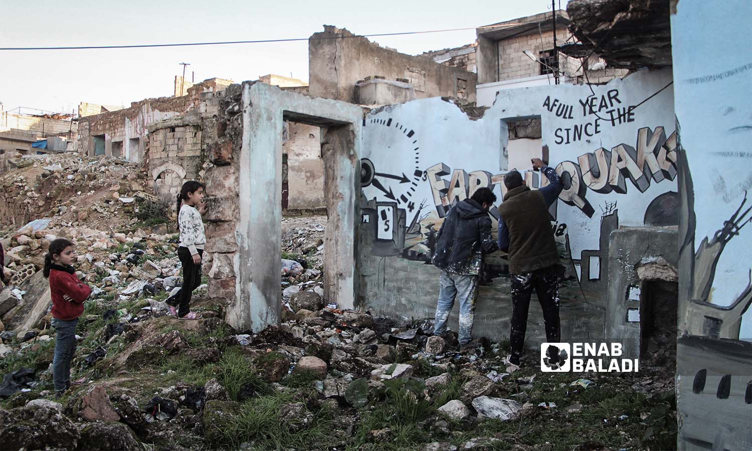 فريق "ريشة أمل" يرسم جدارية على جدران منزل دمره الزلزال في شمال غربي سوريا - 6 من شباط 2024 (عنب بلدي/ عبد الكريم الثلجي)