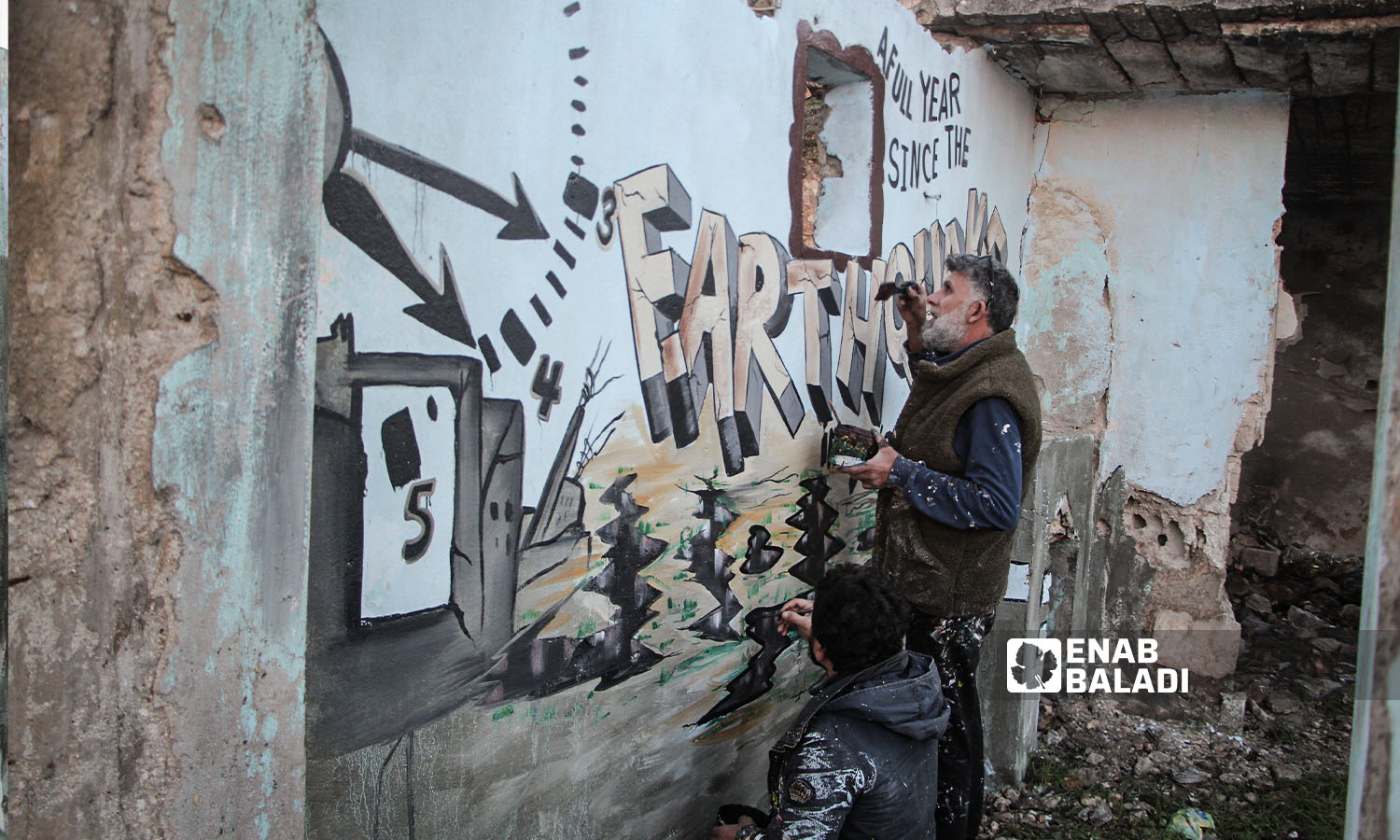شبان يرسمون جدارية إحياء لذكرى كارثة الزلزال في مديمة بنش  - 6 من شباط 2024 (عنب بلدي/ عبد الكريم الثلجي)