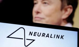 يظهر شعار شركة "نيورالينك" على لوح ذكي، وصورة إيلون ماسك في الخلفية- 19 كانون الأول 2022 (رويترز)