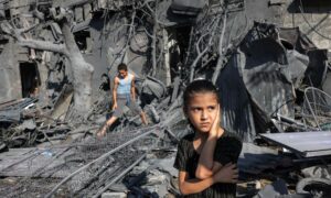 فتاة تقف بجانب الركام أمام مبنى أصيب بالقصف الإسرائيلي على رفح- 31 من تشرين الأول 2023 (AFP)