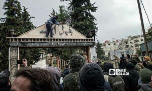 المحتجون يزيزلون اسم باسل الأسد عن مدخل حديقة في محافظة السويداء جنوبي سوريا- 19 من شباط 2024 (عنب بلدي)