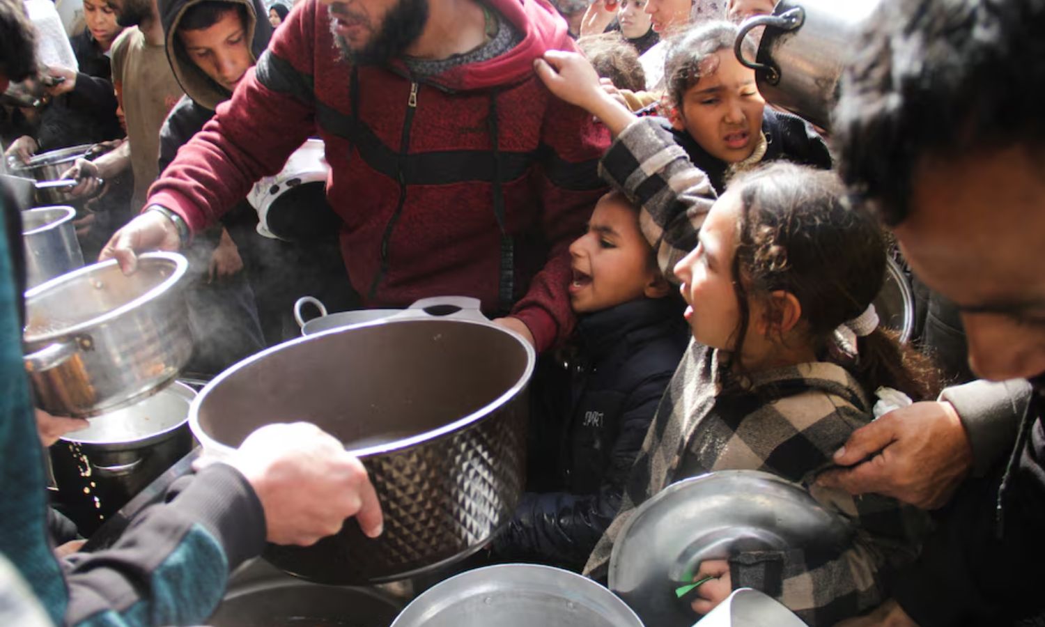 فلسطينيون يجتمعون للحصول على وجبة غذاء في الوقت الذي تتفاقم به المأساة الإنسانية في قطاع غزة- 19 من آذار 2024 (رويترز)