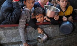 أطفال فلسطينيون ينتظرون الحصول على الطعام المطبوخ في مطبخ خيري وسط نقص الإمدادات الغذائية، ومع استمرار الصراع المستمر بين إسرائيل وحركة 