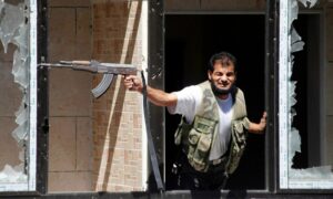 مقاتل من "الجيش السوري الحر" يطلق النار من سلاحه على قصر العدل الذي تسيطر عليه قوات النظام في حلب - 13 من أيلول 2013 (رويترز)
