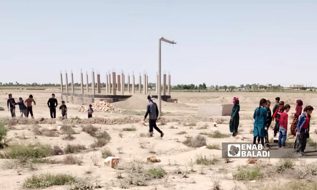 أطفال في بلدة الباغوز بريف دير الزور الشرقي خلال مرورهم فوق بقايا إحدى المقابر الجماعية- 23 من نيسان 2024 (عنب بلدي/ عبادة الشيخ) )