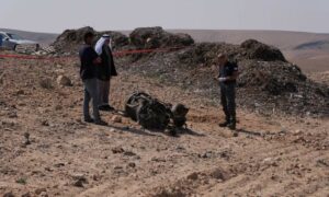 ضابط شرطة إسرائيلي وسكان محليون يتفقدون بقايا صاروخ أطلقته إيران نحو إسرائيل- 14 من نيسان 2024 (رويترز/كريستوف فان دير بير)