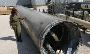 جندية من الجيش الإسرائيلي بجوار صاروخ باليستي إيراني سقط في إسرائيل- 16 من نيسان 2024 (AFP/ جيل كوهين)