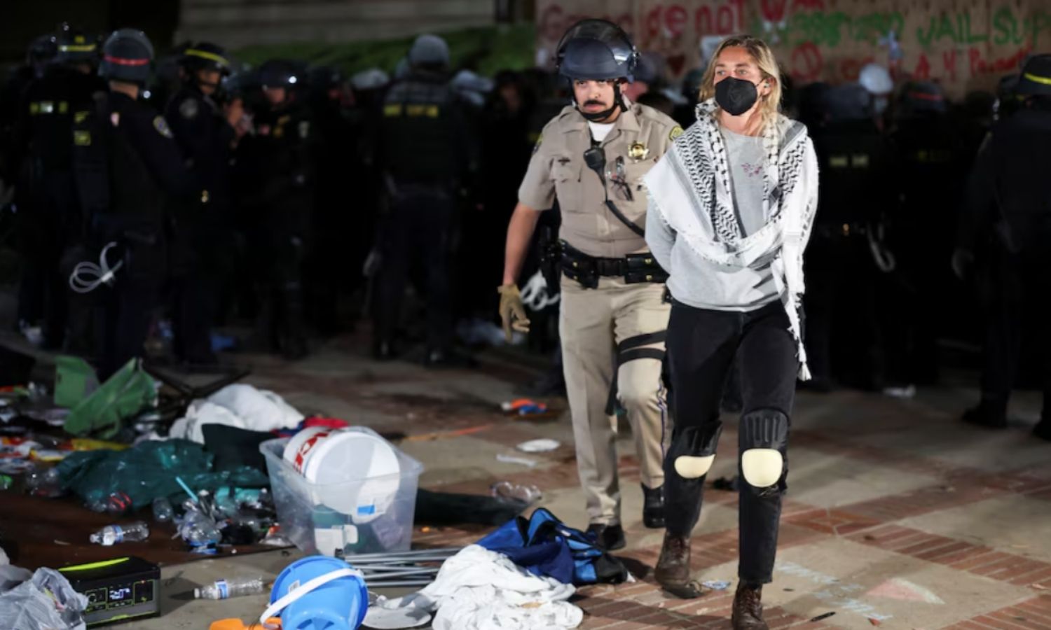 عناصر من شرطة لوس أنجلوس يحتجزون أحد المتظاهرين أثناء قيامهم بإخلاء مخيم الاحتجاج لدعم الفلسطينيين في جامعة كاليفورنيا - 2 من أيار 2024 (رويترز)