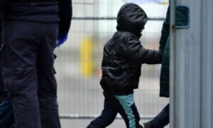 موظف في الهجرة البريطانية يرافق طفلًا مهاجرًا عند وصوله إلى مدينة دوفر البريطانية - كانون الثاني 2023 (AFP)