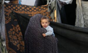 طفل فلسطيني تحمله سيدة خلال نزوح مستمر في قطاع غزة هربًا من الحرب الإسرائيلية المتواصلة على القطاع- 25 من أيار 2024 (أونروا/ إكس)