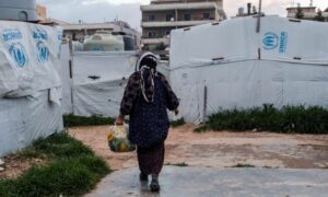 لاجئة سورية تسير بالقرب من الخيام في مخيم غير رسمي في المرج بالبقاع بلبنان - 5 من نيسان 2024 (رويترز)