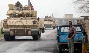 سكان يقفون في أحد الشوارع خلال دورية مشتركة لـ"قوات سوريا الديمقراطية" التي تقودها الولايات المتحدة في ريف القامشلي - 8 من شباط 2024 (رويترز)
