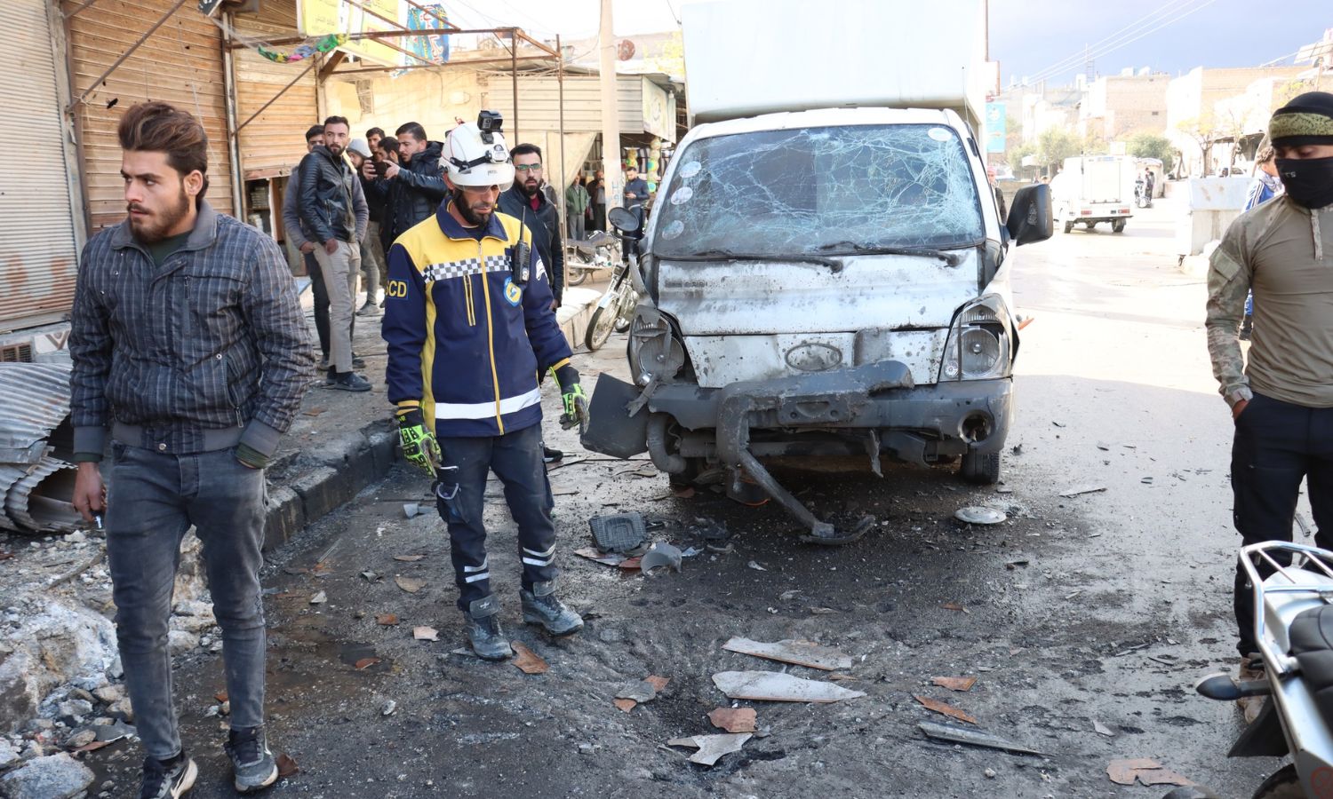 متطوع في الدفاع المدني السوري ومدنيون يتفقدون موقعًا سقطت فيه قذيفة صاروخية في مدينة الباب- 24 من تشرين الثاني 2024 (الدفاع المدني السوري)