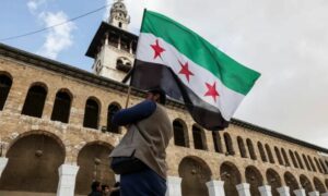 مواطن سوري يرفع علم الثورة السورية في المسجد الأموي بدمشق (رويترز)