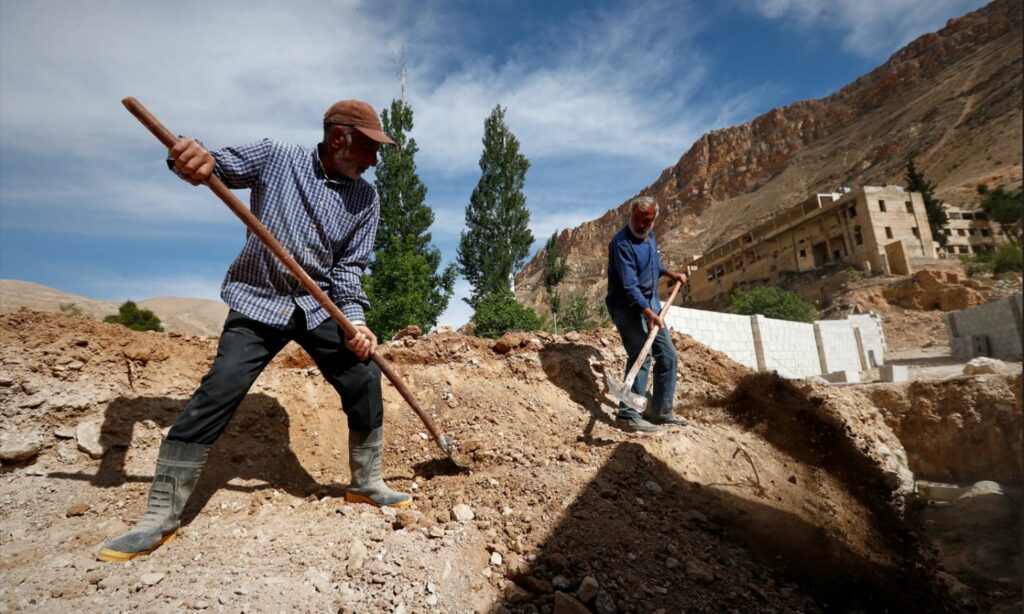 مواطنون يعملون على بناء أملاكهم المدمرة في عين الفيجة في وادي بردى بريف دمشق - 8 أيار 2025 (AP/ عمر صناديقي)