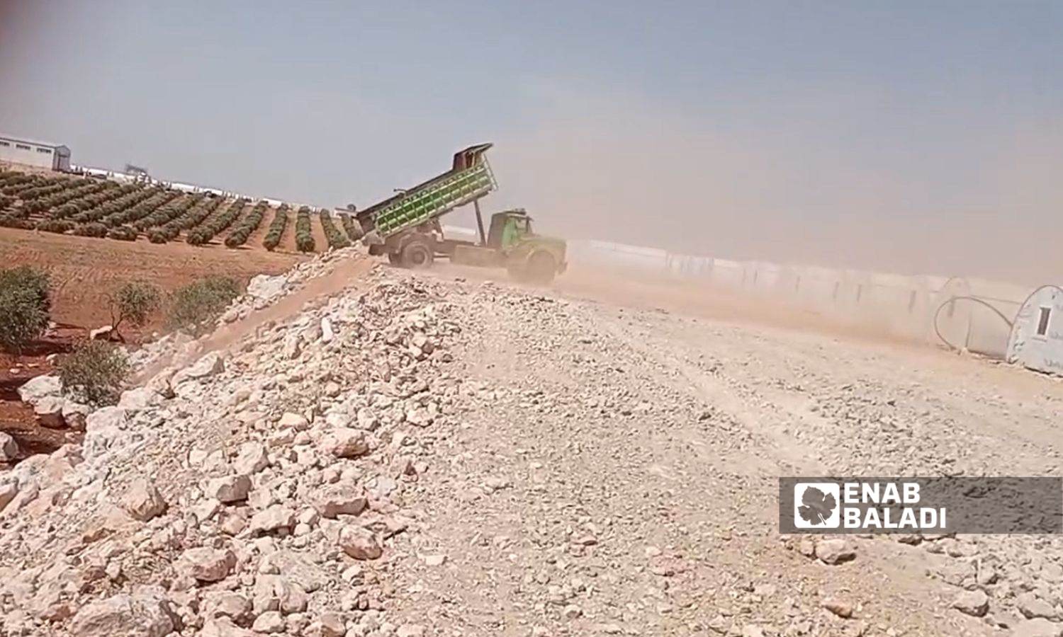 آلية تشارك ببناء مخيم بالقرب من أراضي زراعية بريف حلب الشمالي (عنب بلدي)