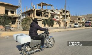 شاب يحمل قوالب الثلج على دراجته بحي الرصافة بمدينة دير الزور شرقي سوريا - 11 آذار 2025 (عنب بلدي/ عبادة الشيخ)
