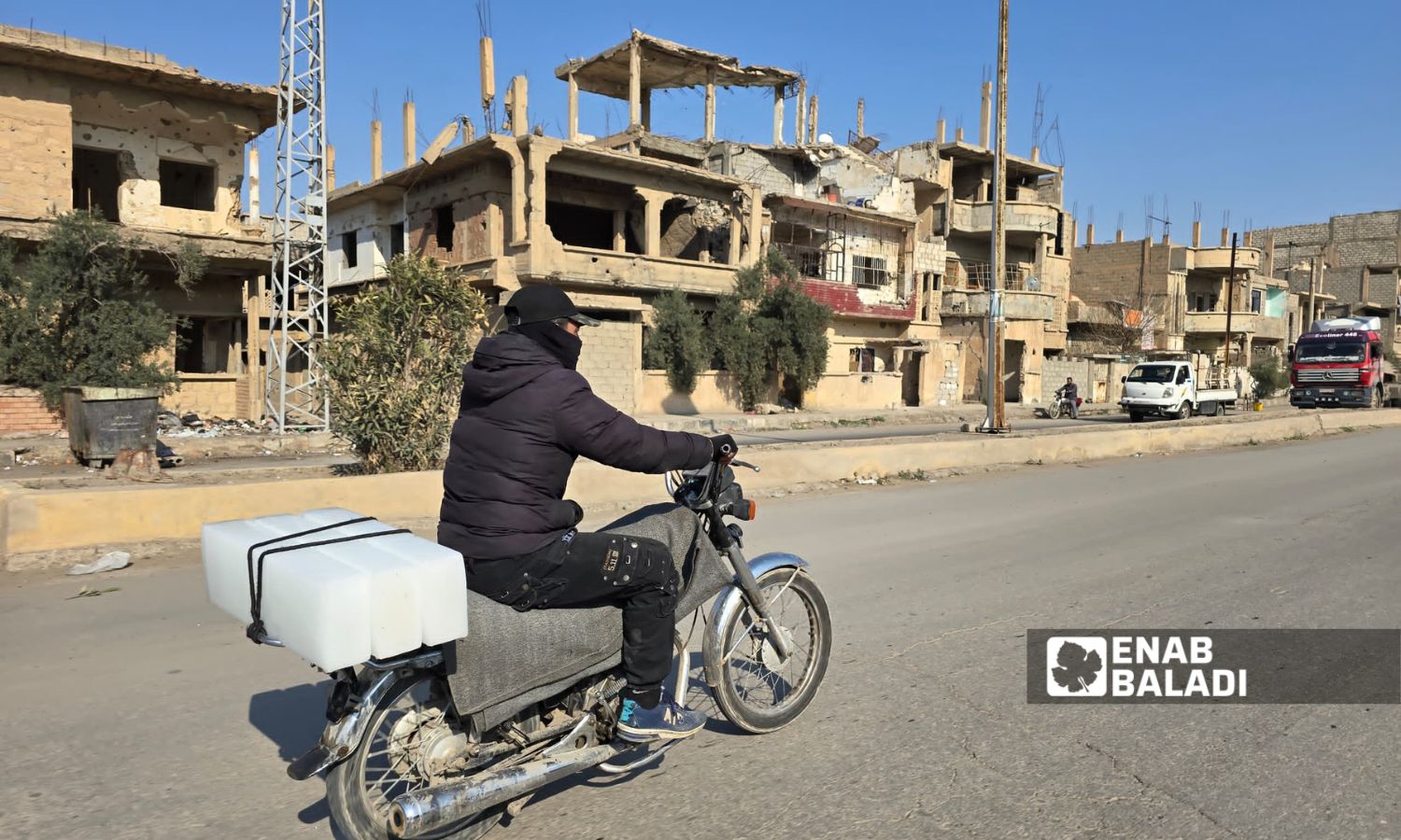 شاب يحمل قوالب الثلج على دراجته بحي الرصافة بمدينة دير الزور شرقي سوريا - 11 آذار 2025 (عنب بلدي/ عبادة الشيخ)