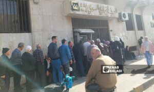 موظفون حكوميون يقفون في طابور أمام المصرف التجاري السوري بانتظار تسلم رواتبهم وسط مدينة حمص- 27 من آذار 2025 (عنب بلدي/ جنى العيسى)

