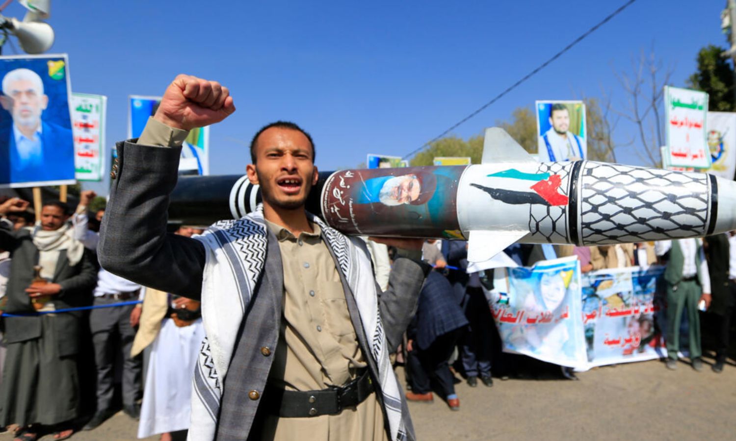 رجل يمني يحمل مجسما لصاروخ مزينا بألوان العلم الفلسطيني والكوفية أمام صور زعيم حماس الراحل يحيى السنوار وزعيم الحوثيين عبد الملك الحوثي خلال احتجاج في صنعاء للتنديد بالضربات على اليمن والقصف الإسرائيلي لغزة 15 كانون الثاني 2025 (فرانس برس)