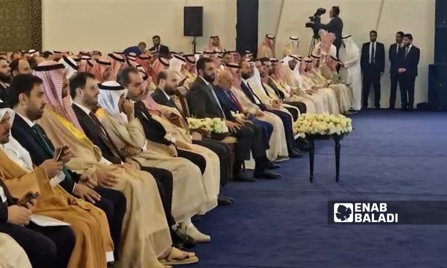 الرئيس السوري للمرحلة الانتقالية أحمد الشرع إلى جانب شخصيات حكومية ورجال أعمال سوريين وسعوديين - 24 تموز 2025 (عنب بلدي)