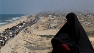 سيدة تراقب الفلسطينيين النازحين من شمال غزة بسبب العملية العسكرية الإسرائيلية 17 أيلول 2025 (رويترز)