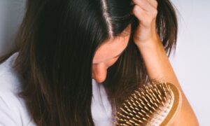سيدة تشعر بالاستياء نتيجة تساقط شعرها أثناء تصفيفه (كانفا)
