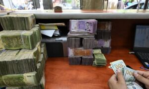 موظف في أحد مكاتب الصرافة بدمشق يعدّ عملة سورية - 21 أيار 2025 (AFP)
