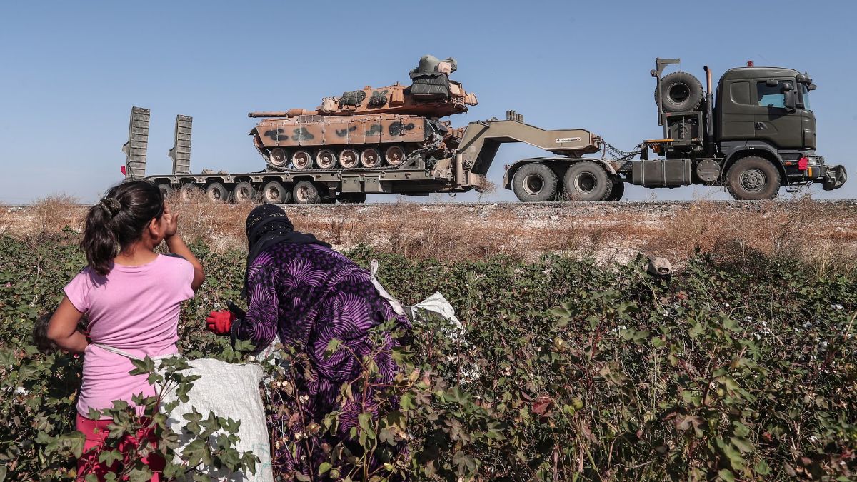 عمال زراعيون يراقبون مركبات عسكرية تركية في طريقها إلى شمال سوريا - 12 تشرين الأول 2019 - (وكالة حماية البيئة/ سادات سونا)