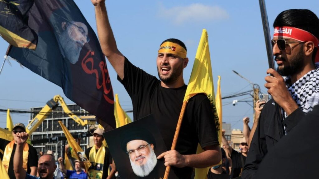 أحد مناصري حزب الله اللبناني يرفع علمًا عليه صورة الأمين العام السابق للحزب - 27 أيلول 2025 (رويترز)