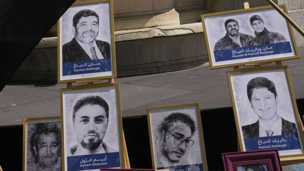صور لباتريك الدباغ ووالده مازن الدباغ، اللذان يتهم النظام السوري السابق بتصفيتهما داخل معتقلاته، جرى رفعهما خلال مظاهرة أمام محكمة الجنايات في باريس - 21 أيار 2024 (أسوشيتيد برس)