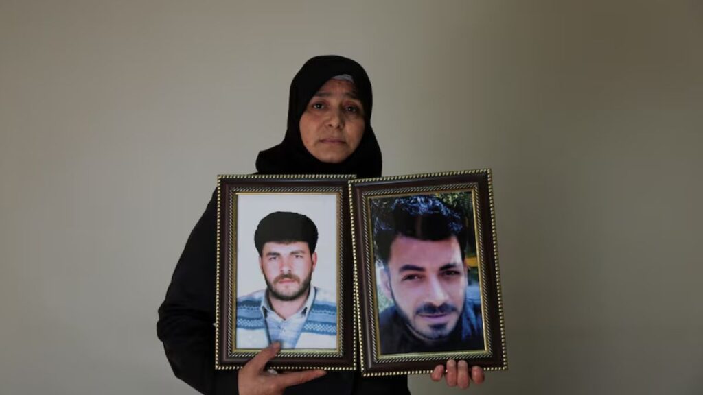 امرأة سورية ترفع صورة ولديه المختفيين في سجون نظام الأسد - 13 تشرين الثاني 2025(رويترز)