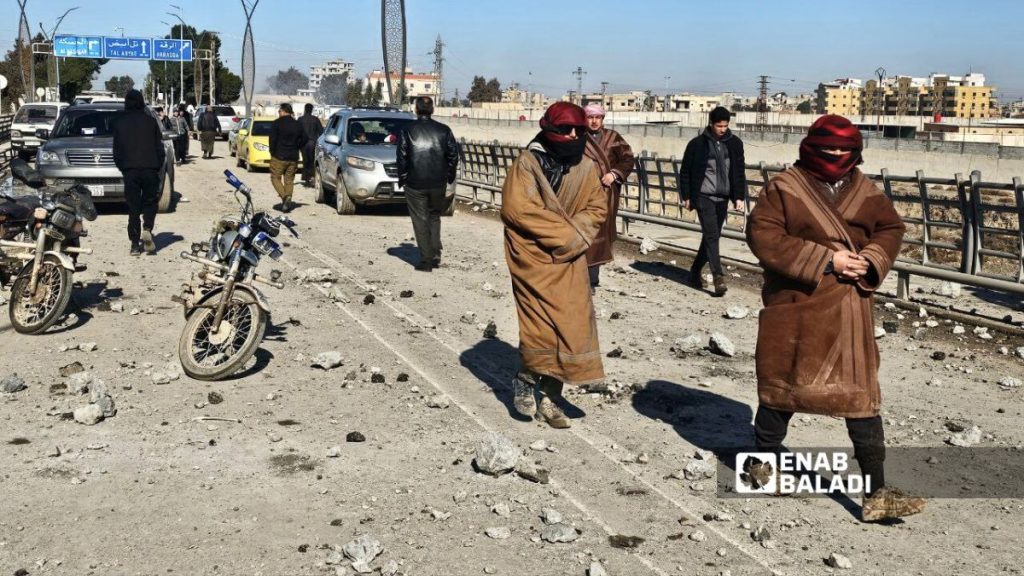 مدنيون يقفون أمام جسر الرشيد في الرقة شمالي سوريا بعد تدميره جراء العمليات العسكرية بين الجيش السوري وقوات سوريا الديمقراطية - 19 كانون الثاني 2026 (عنب بلدي/إياد عبد الجواد)