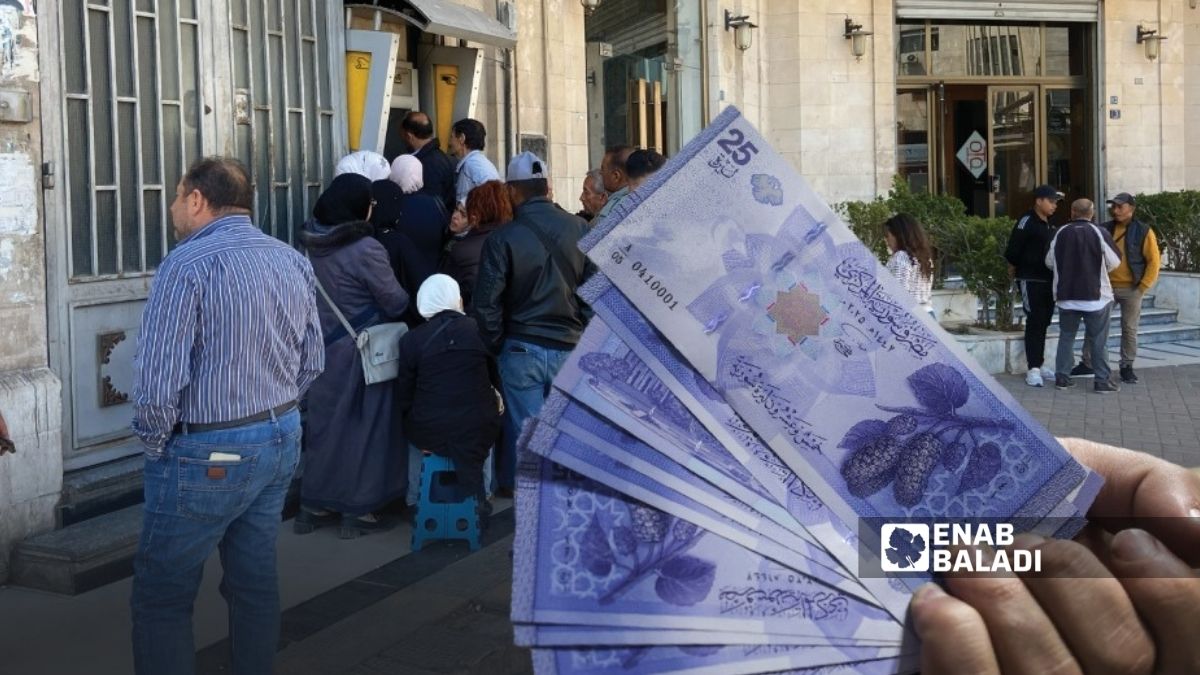 موظفون حكوميون ينتظرون على طابور لسحب رواتبهم من صراف آلي في ساحة المرجة بدمشق - 14 نيسان 2025 (عنب بلدي)