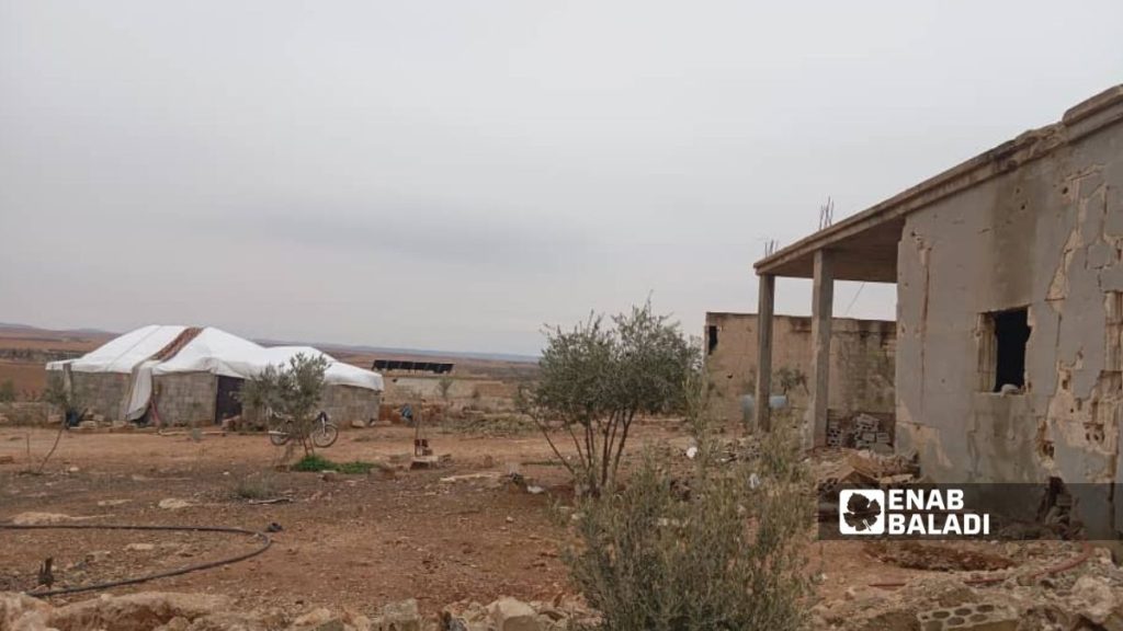 أحد سكان قرية حمادة عمر بناحية عقيربات في ريف حماة الشرقي يبني خيمة بجانب منزله المدمر - 22 كانون الثاني 2026 (عنب بلدي)