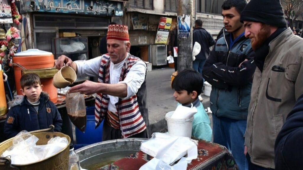 بائع عرقسوس وزبائن أمام بسطة وسط حي الجميلية بمدينة حلب- 1 آذار 2025 (سانا)