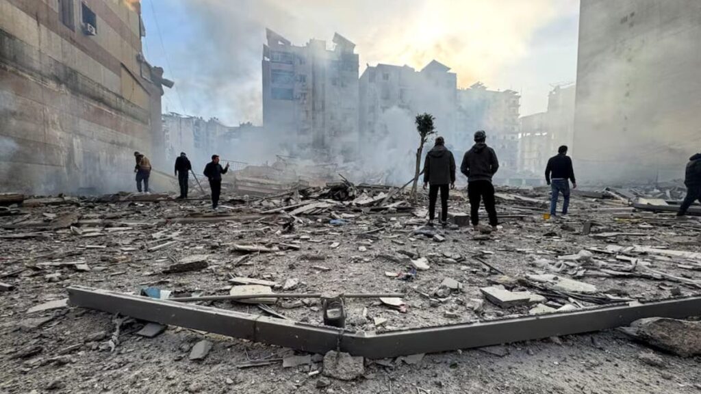 أشخاص يقفون على أنقاض مبنى متضرر بعد غارة إسرائيلية على الضاحية الجنوبية لبيروت -6 آذار 2026 (عنب بلدي)