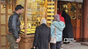 عائلة سورية تستعرض المشغولات الذهبية أمام واجهة محل للمصوغات والحلي في سوق الذهب بالحريقة في دمشق القديمة - 25 شباط 2026 (عنب بلدي/أحمد مسلماني) 
