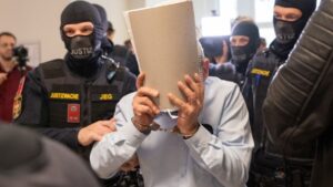 ضابط سوري سابق متهم يغطي وجهه أثناء اقتياده إلى قاعة المحكمة الإقليمية في فيينا بالنمسا - 1 حزيران 2026 (AFP)