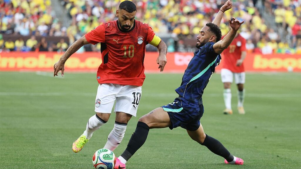 قائد المنتخب المصري محمد صلاح يتنافس على الكرة مع ماتيوس كونيا لاعب المنتخب البرازيلي خلال اللقاء الودي بين مصر و البرازيل في ملعب هنغنتون بانك فيلد - 7 حزيران 2026 (وكالة فرانس برس)