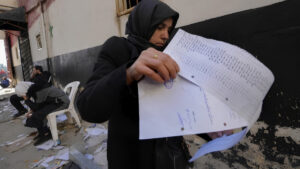 امرأة تتصفح قائمة أسماء في وثيقة عثرت عليها في سجن 