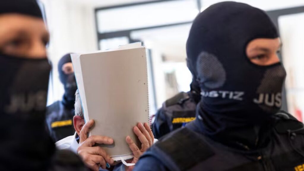 ضابط سوري سابق متهم يغطي وجهه أثناء اقتياده إلى قاعة المحكمة الإقليمية في فيينا بالنمسا - 1 حزيران (رويترز/ ليزا لويتنر )