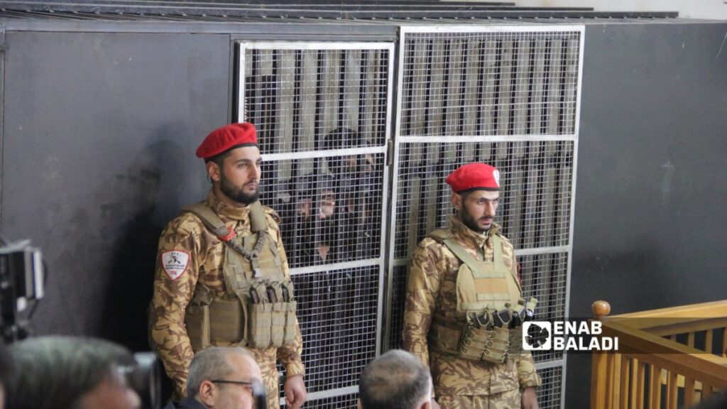 عنصران حكوميان وعدد من الأشخاص داخل محكمة الجنايات بالقصر العدلي في مدينة حلب- 8 آذار 2026 (عنب بلدي)