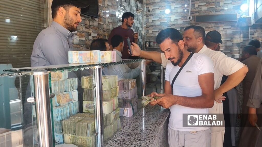 مواطنون يستبدلون ما لديهم من عملة سورية قديمة بعملة جديدة قبل يوم من نهاية مهلة الاستبدال في مركز الاستبدال الوحيد للعملة بمدينة الرقة شمال شرق سوريا - 29 تموز 2026 (عنب بلدي/أحمد الحمدي)