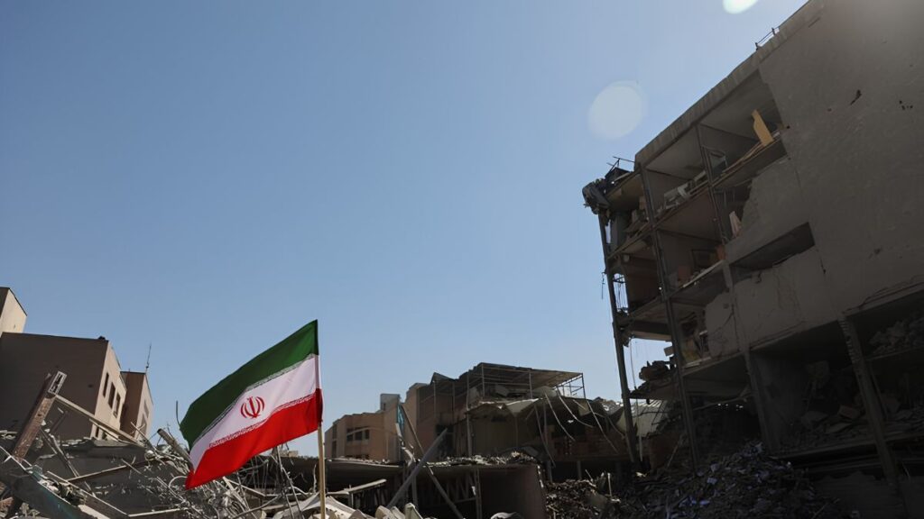 العلم الإيراني وسط أبنية مدمرة في طهران جراء استهدافها بغارة جوية - 3 آذار 2026 (رويترز)