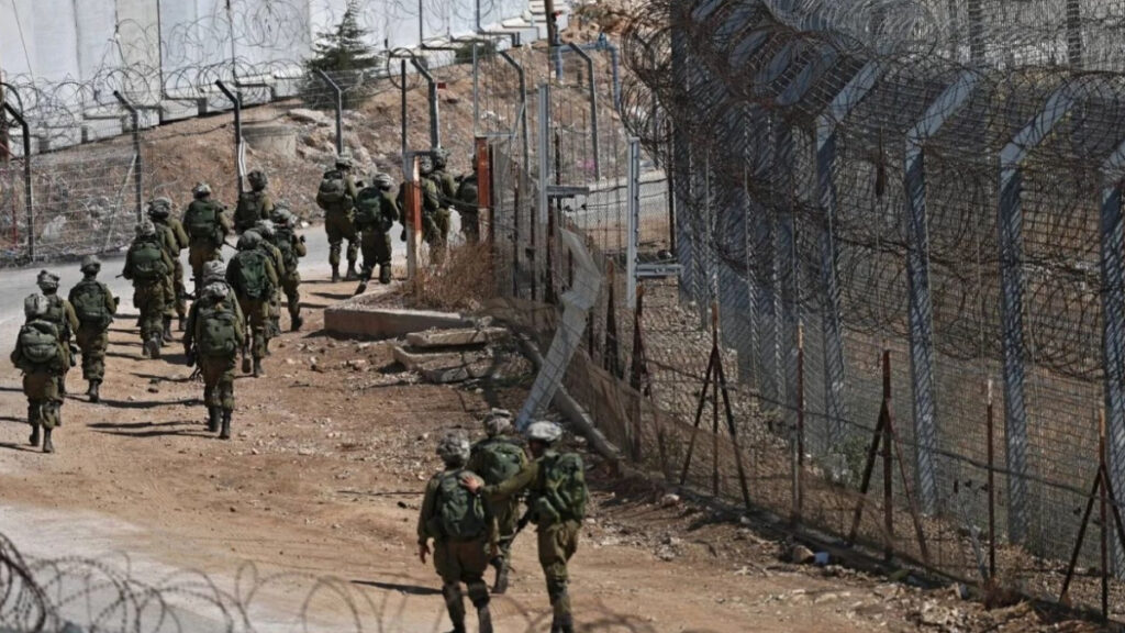 جنود إسرائيليون يسيرون بجانب خط وقف إطلاق النار بين الجولان السوري المحتل والأراضي السورية في المنطقة العازلة - 22 تموز 2025 (AFP)