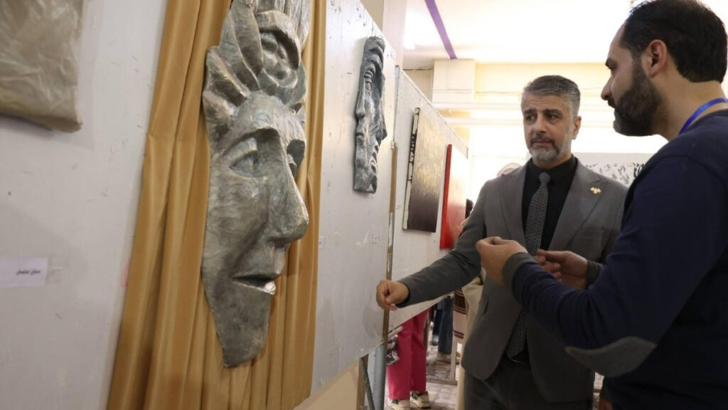 رئيس جامعة حلب أسامة رعدون وطالب في كلية الفنون الجميلة أمام عمل نحتي في افتتاح مؤتمر ومعرض للكلّية - 24 نيسان 2026 (كلية الفنون الجميلة التطبيقية/فيسبوك)