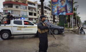 عنصر للأمن العام السوري وبخلفه سيارة تابعة لمديرية الأمن الدخلي في مدينة اللاذقية- 25 كانون الأول 2025 (سانا)