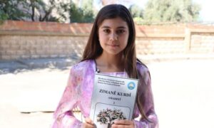 طالبة تحمل كتاب اللغة الكردية خلال احتجاج بمعبدة في الحسكة – 18 أيلول 2026 (هاوار)