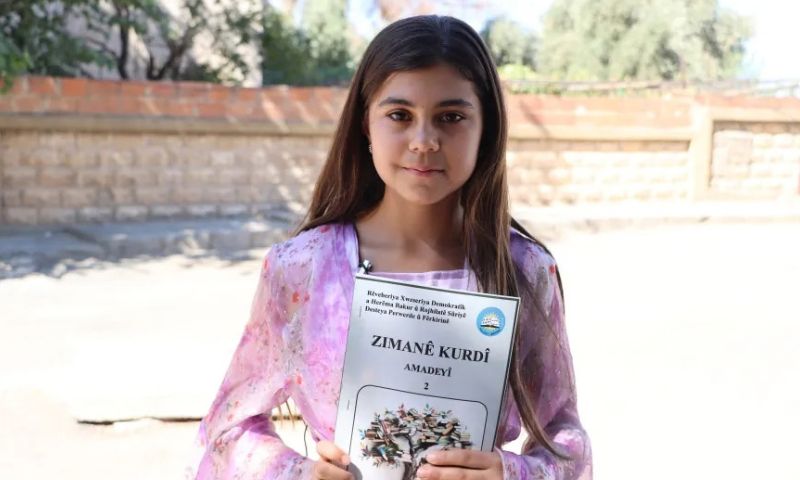 طالبة تحمل كتاب اللغة الكردية خلال احتجاج بمعبدة في الحسكة – 18 أيلول 2026 (هاوار)